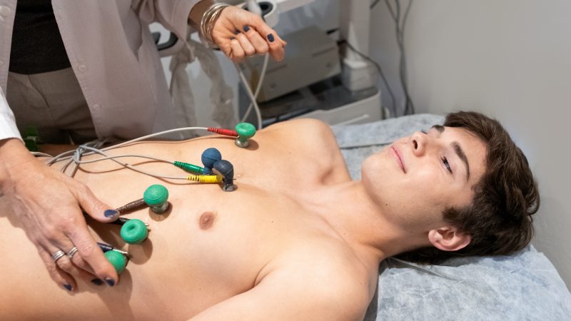 Cardiologist performing an electrocardiogram on a teenage male patient